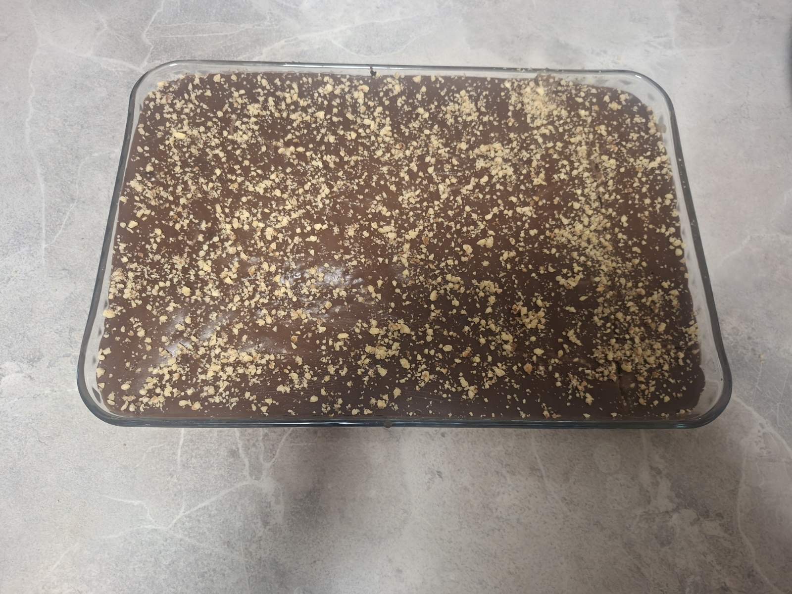 Tortë me çokolladë e mbuluar me çokolladë dhe arra të grira